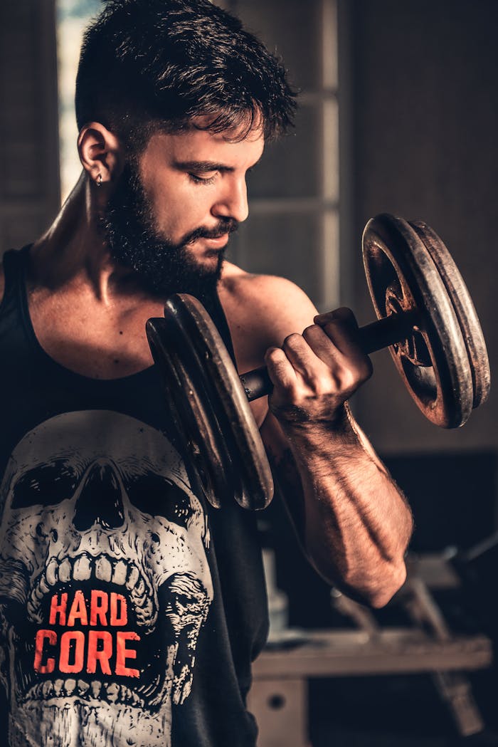 Home Bearded man in gym lifting a heavy dumbbell, showcasing strength and fitness.